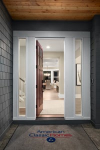 Front door with floor to ceiling windows on either side of the window with white trim.