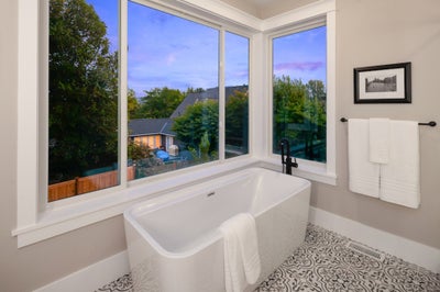 Soaking tub sits below large window.