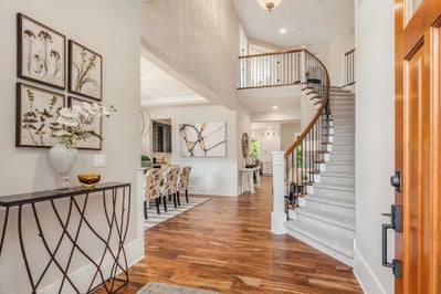 A staircase sits next to the front entrance and is open to formal dinning space.