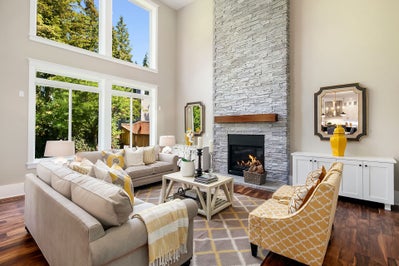 Living room featuring 4 large windows and a fire place surrounded by floor to ceiling stone.