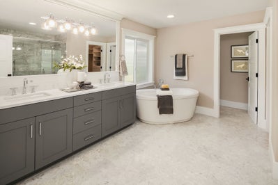 Duel sink gray vanity with white stone countertops sits next to large soaking tub.