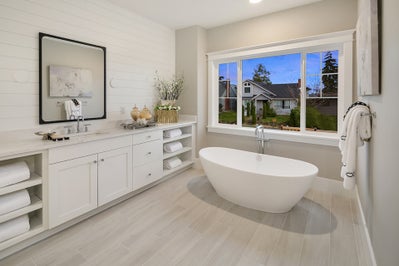 Soaking tub, large window, white vanity with built in shelves on either side.