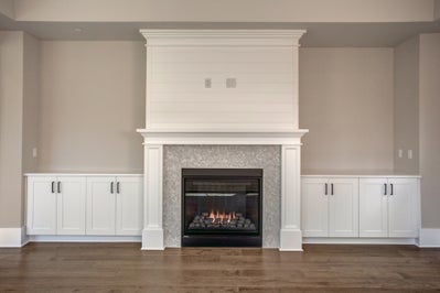 Fireplace with ship lap above and built in cabinets on both sides.