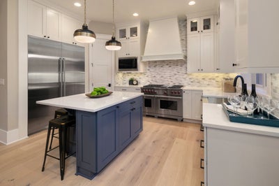 Kitchen with industrial stainless steel fridge, white cabinets with blue accents cabinets in the island.