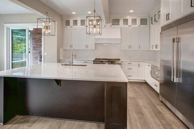 Kitchen features white cabinets and white countertops. The island stands out with dark cabinets.