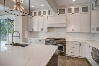 Kitchen featuring cabinet storage to the ceiling with a hooded range that is white to match the cabinets.