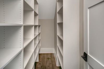 Walk in pantry with built in wooden shelving.