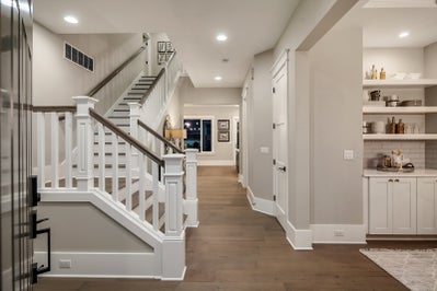 Staircase leads into entryway facing the kitchen.