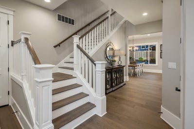 Entryway with staircase and hall way leading to dinning room.