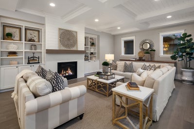 Great room with fireplace at the center surrounded by white tile with built in shelfs and cabinets on either side.