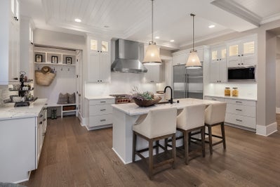 Kitchen with white cabinets, white stone counter tops and stainless steel appliances.