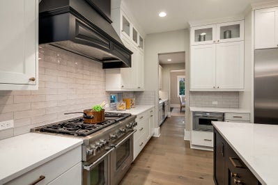Kitchen with Buttler's pantry, white cabinets and black hooded range