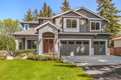 gray house with three car garage, white trim and stone accents