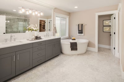 Soaking tub in the corner of a bathroom with a gray double sink vanity
