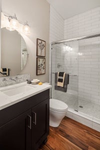 Quaint bathroom with tiled shower, black vanity and a round mirror