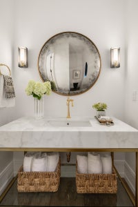 Stone vanity is open below with gold finishes.