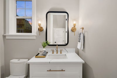 Bathroom vanity with gold finishes and black mirror