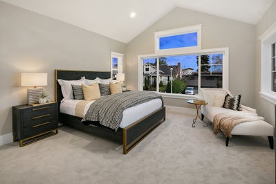 Master bedroom with large window and vaulted ceiling.