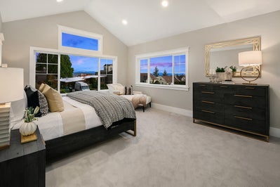 Master bedroom with large window and vaulted ceiling.
