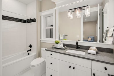 Tilled shower, white cabinets with black stone countertop and large mirror