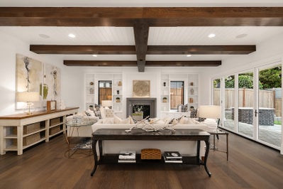 Large great room with an electric frieplace, built in cabinets and dark stained ceiling beams.