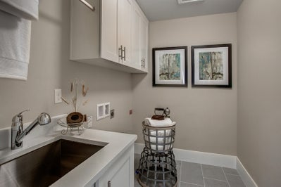 Laundry room with sink and white cabinets.