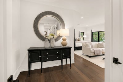 Entryway to master bedroom features entry table and round mirror.