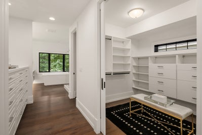 Master closet features sliding door and built in wood shelving.