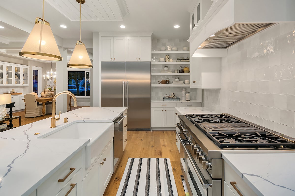 Kitchen with white cabinets, white stone countertops and gold accents.