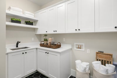 Laundry room with sink, folding counter and white cabinets.