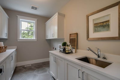 Laundry room with sink, folding counter and white cabinets.