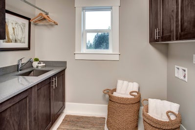 Laundry room with sink, dark wood cabinets and hanging space.