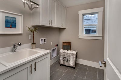 Laundry room with sink and white cabinets.