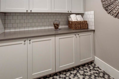 Folding counter in laundry room with white cabinets and gray stone countertops.