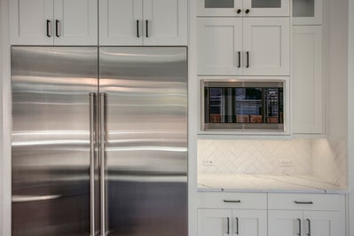 Large fridge with cabinets above and a microwave built in to the right.