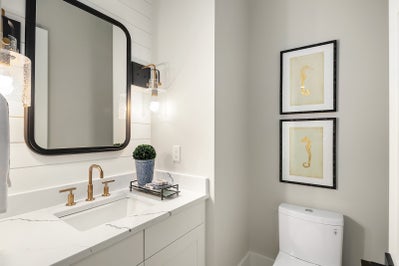 Quaint bathroom with white vanity and gold finishes.