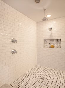 Large walk in shower with two shower heads and tile surround.