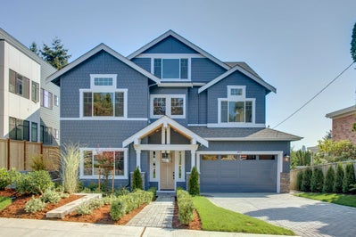 Three story blue house with a two car garage and white trim.