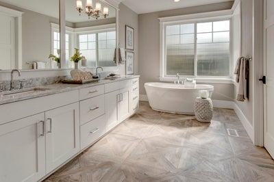 Large master suite with a double sink vanity, natural light and a soaking tub.