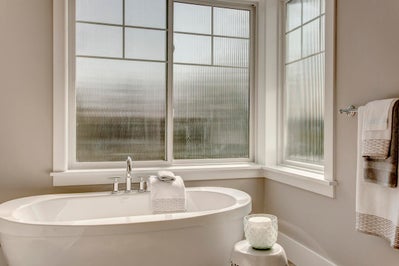 Soaking tub sits below a privacy window.
