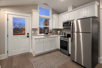 Private kitchen includes fridge, oven and microwave as well as white cabinets and white stone countertops.