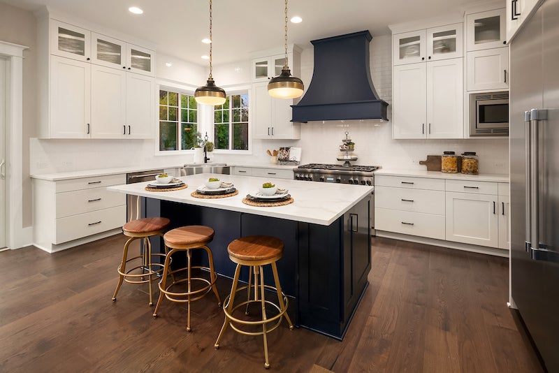 Kitchen with white cabinets and white stone countertops and a navy blue island.