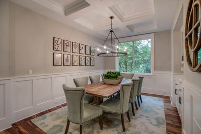 Formal dinning room with custom lighting, white ceiling beams and  white wainscoting.