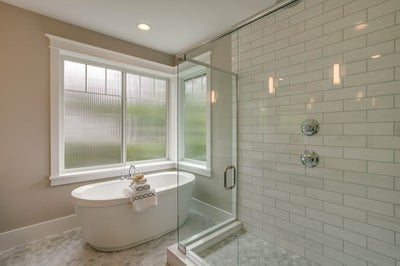 Glass incased shower with tile surround sits next to a soaking tub.