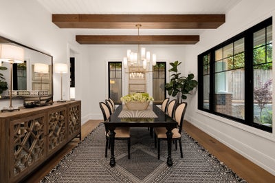 Formal dinning space with black window trim. chandelier and dark beams on the ceiling.