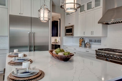 Large island with white stone countertops in a kitchen with white cabinets